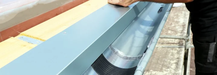 Person bringt Dachrinne an